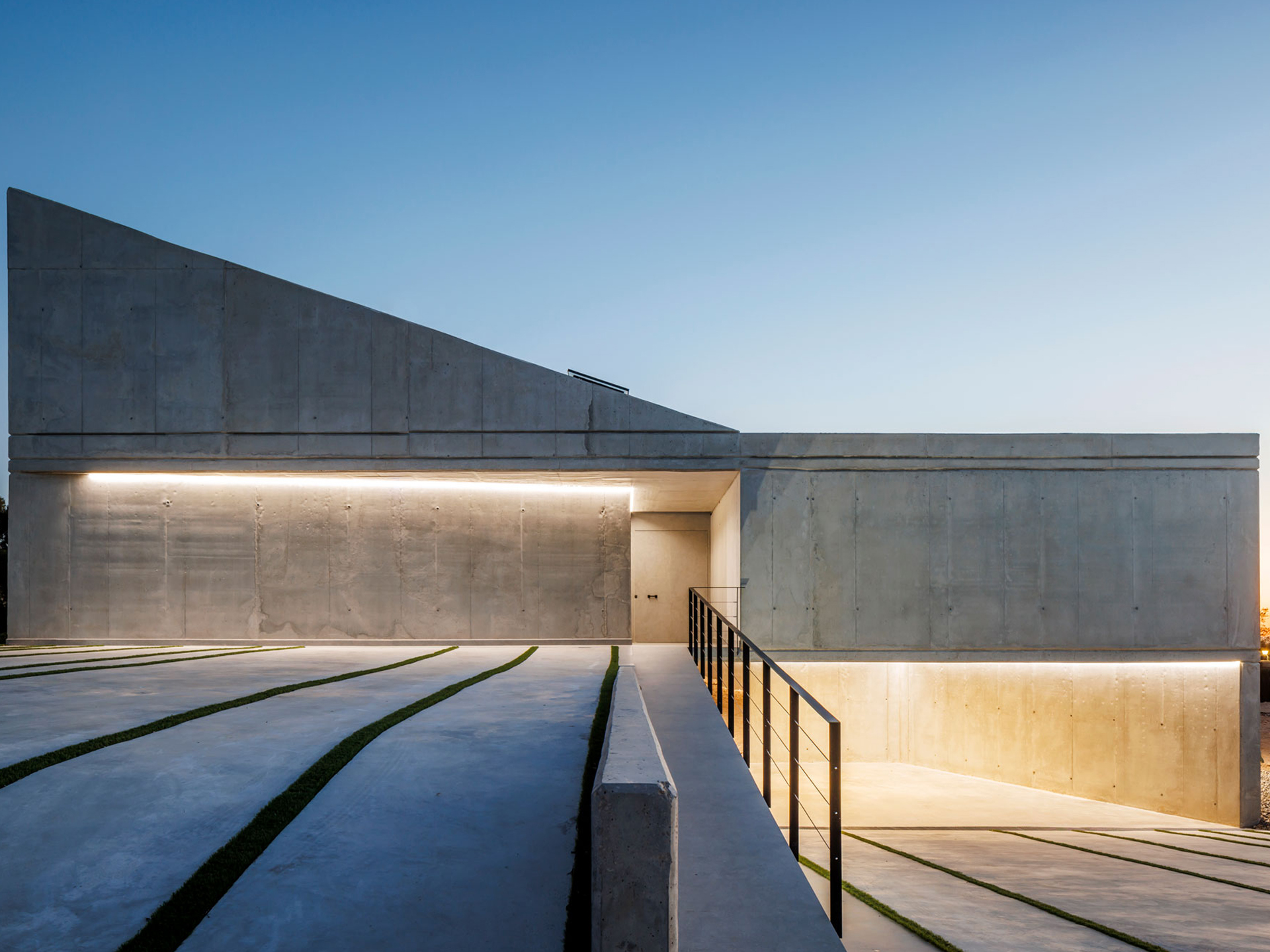 Casa moderna que emerge discretamente detrás de un muro de piedra, fusionando la privacidad con la estética minimalista.